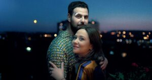 L'amour c'est surcoté - le film : Hakim Jemili et Laura Felpin posent devant un décor urbain, à la nuit tombée